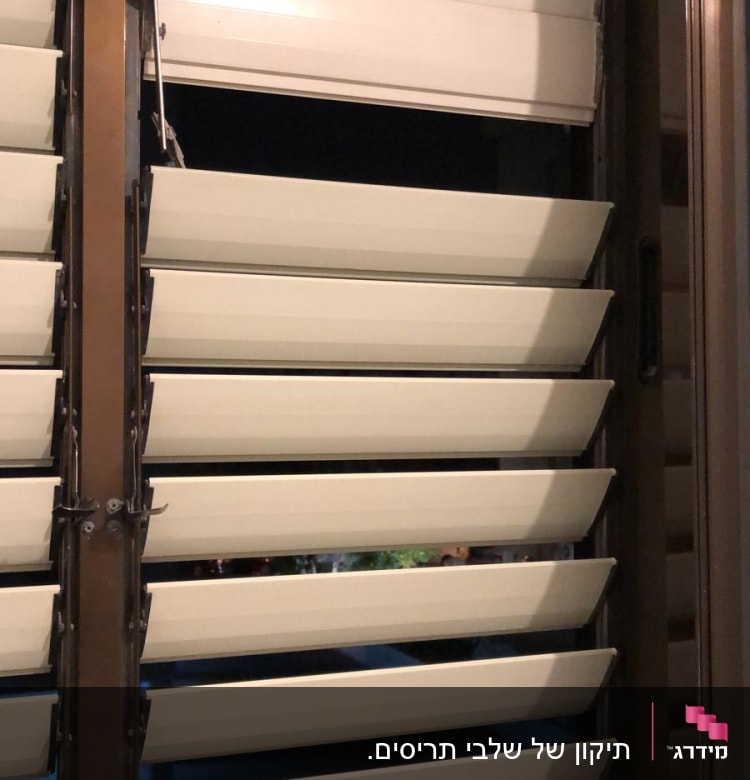 תריסים לבנים פתוחים למחצה עם מסגרת חומה